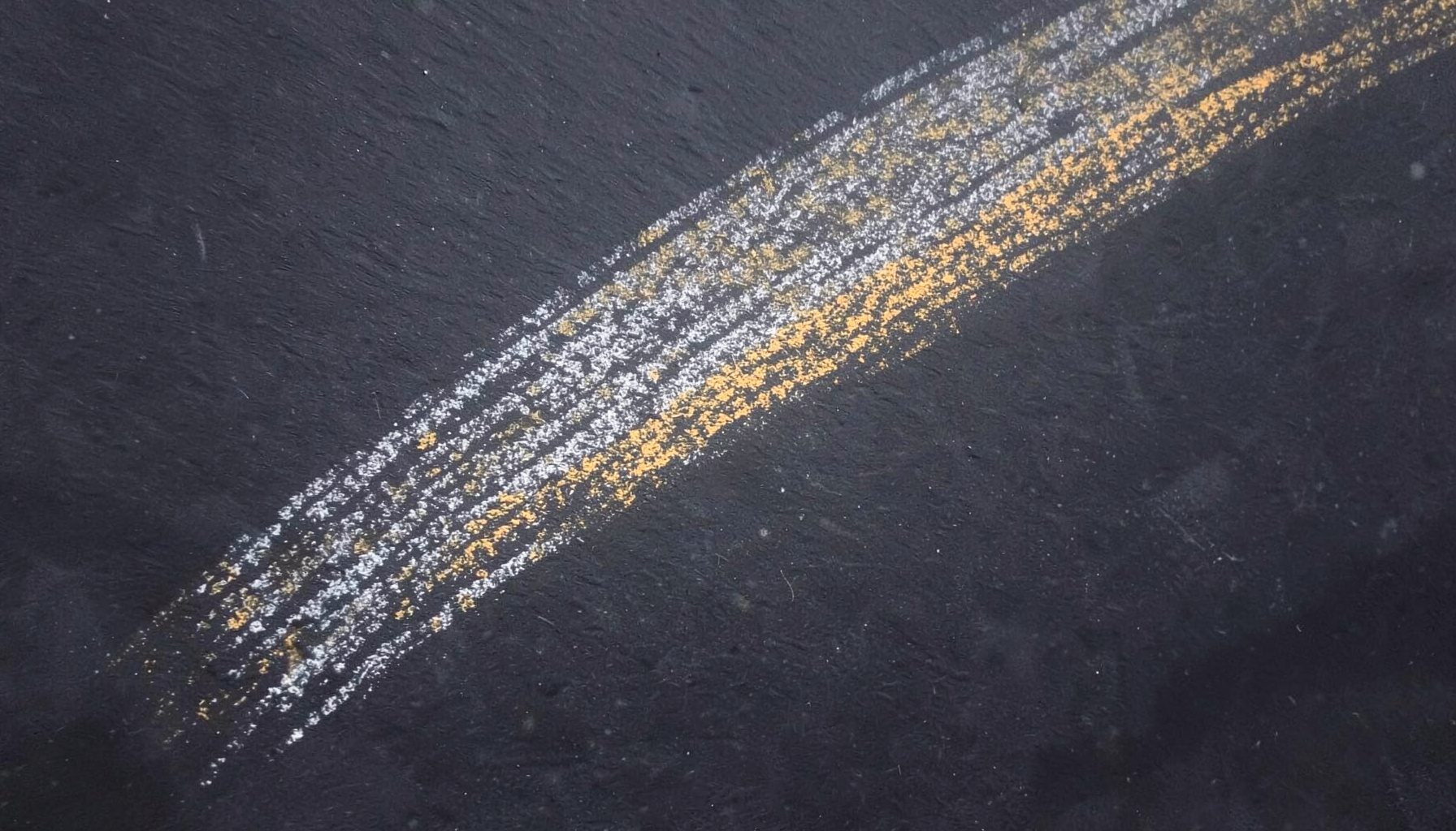 A softly lit chalk drawing on a dark slate board, pale white and warm gold strokes forming a quiet beam of light across the surface